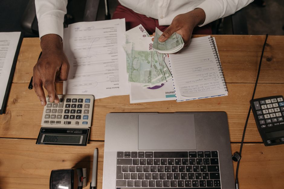 Osoba broji gotovinu uz dokumente i laptop u uredu